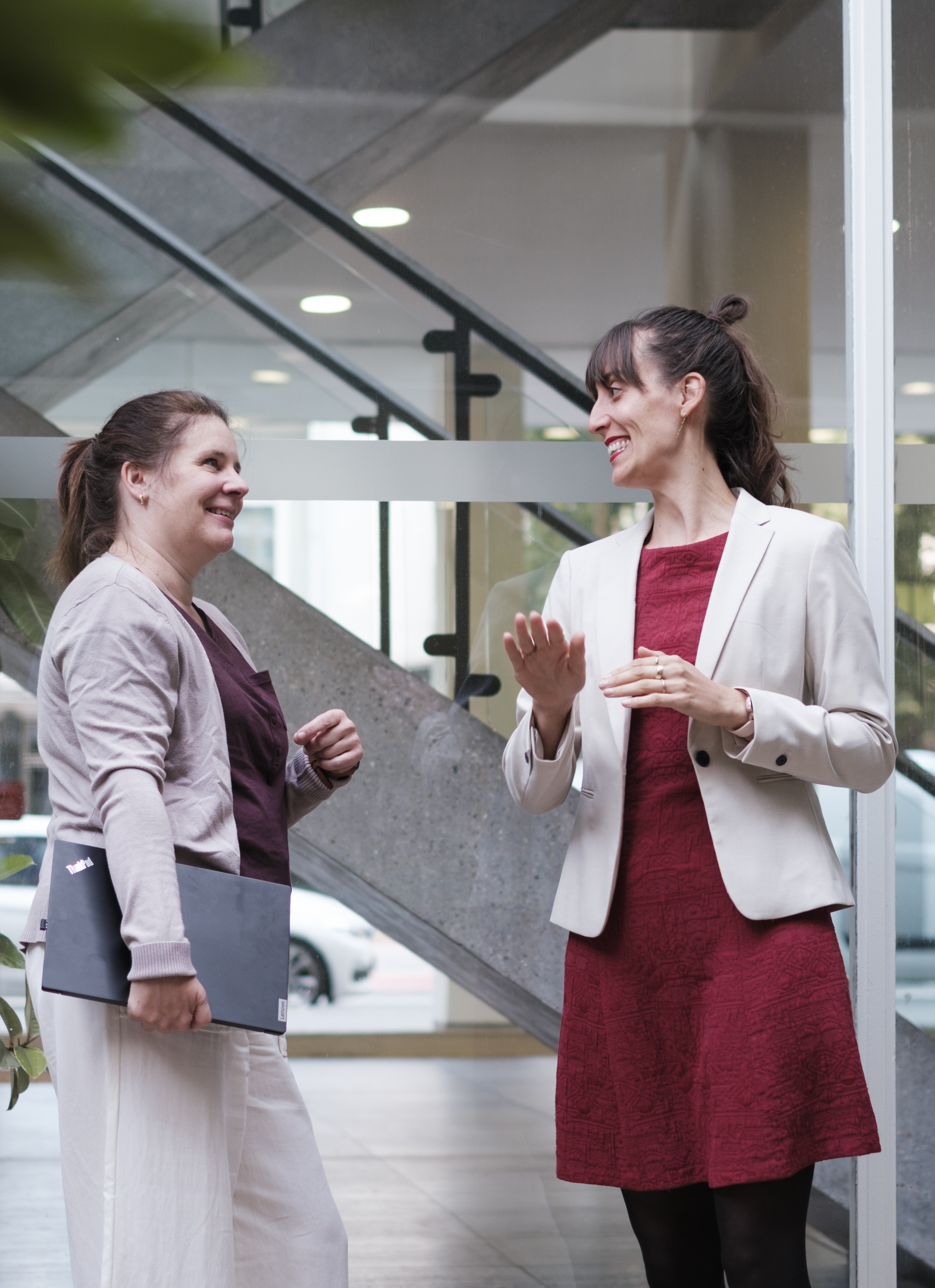 Zwei Frauen stehen vor einer Treppe und unterhalten sich.