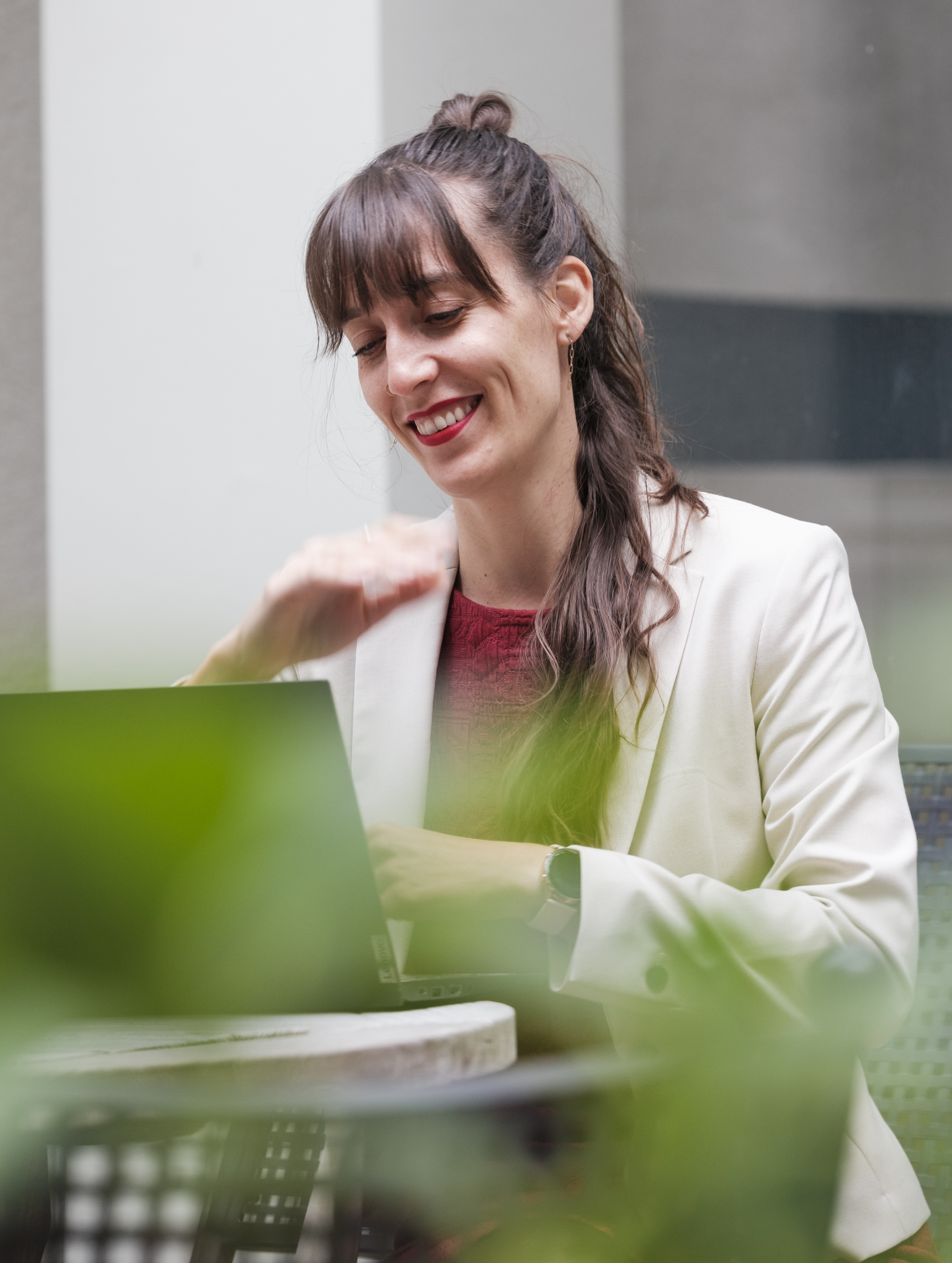 Eine Frau sitzt am Tisch und arbeitet an einem Laptop.