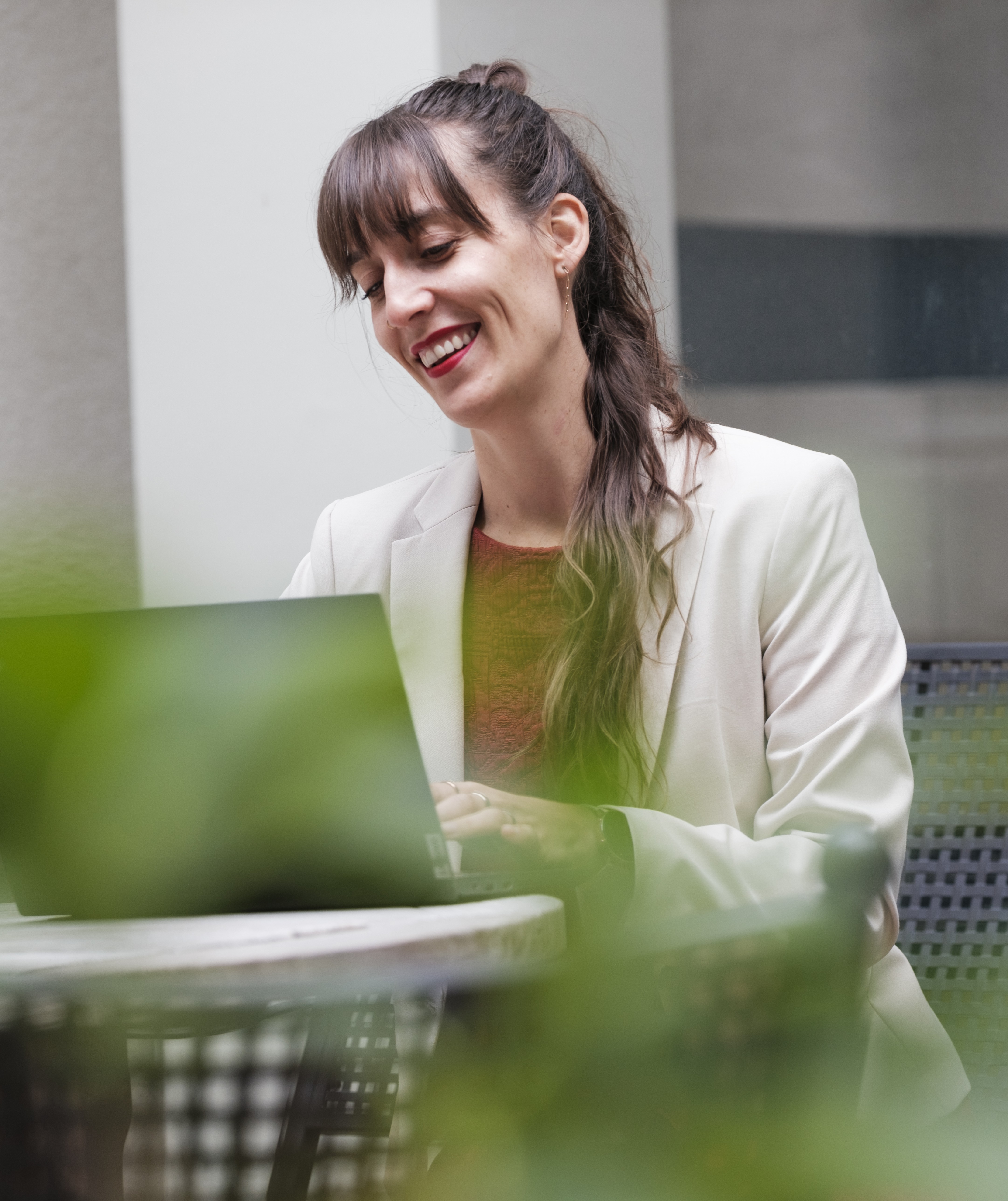 Eine Frau schaut lächelnd auf den Laptop-Bildschirm.