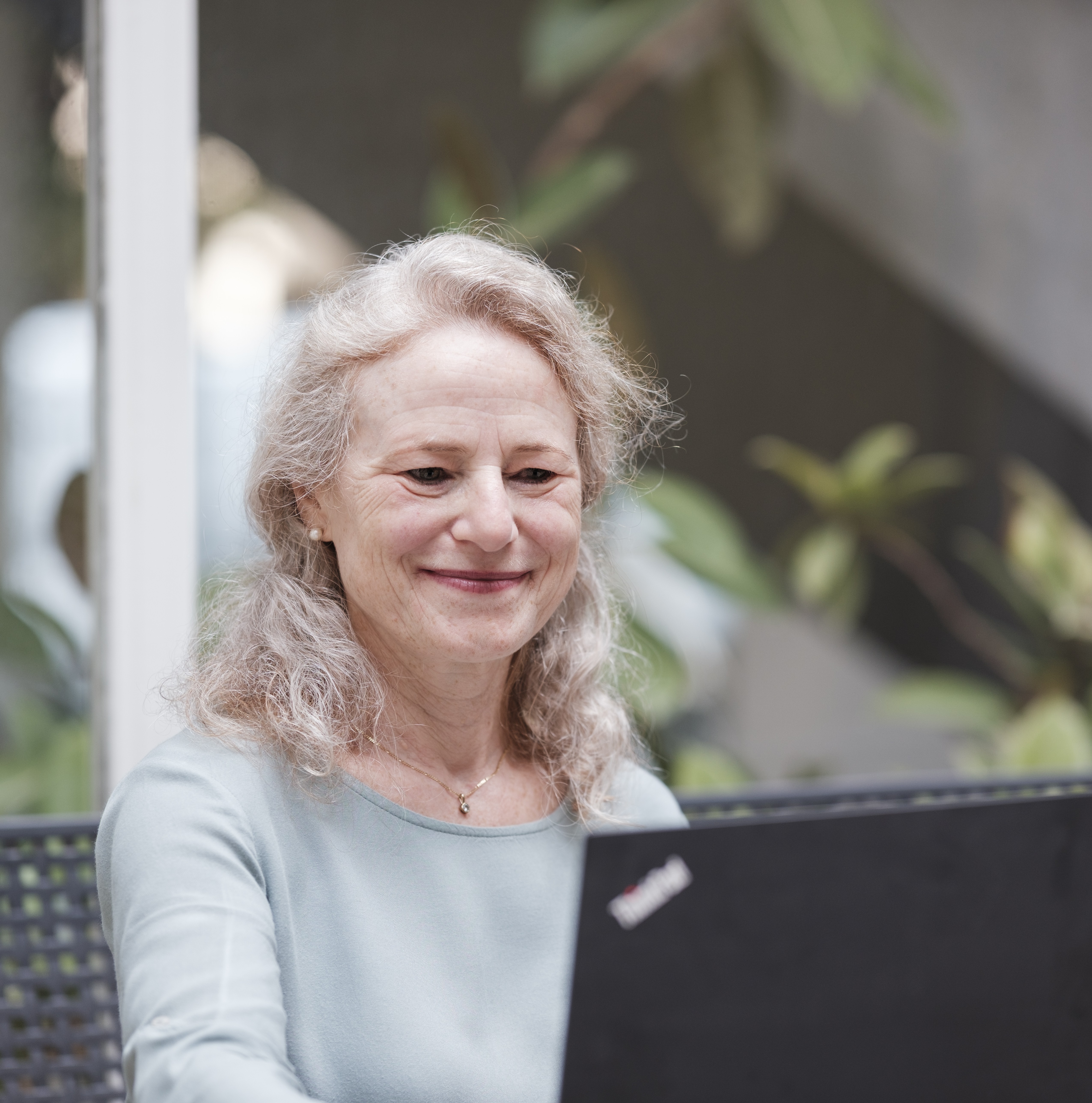 Eine Frau schaut lächelnd auf den Laptop-Bildschirm.