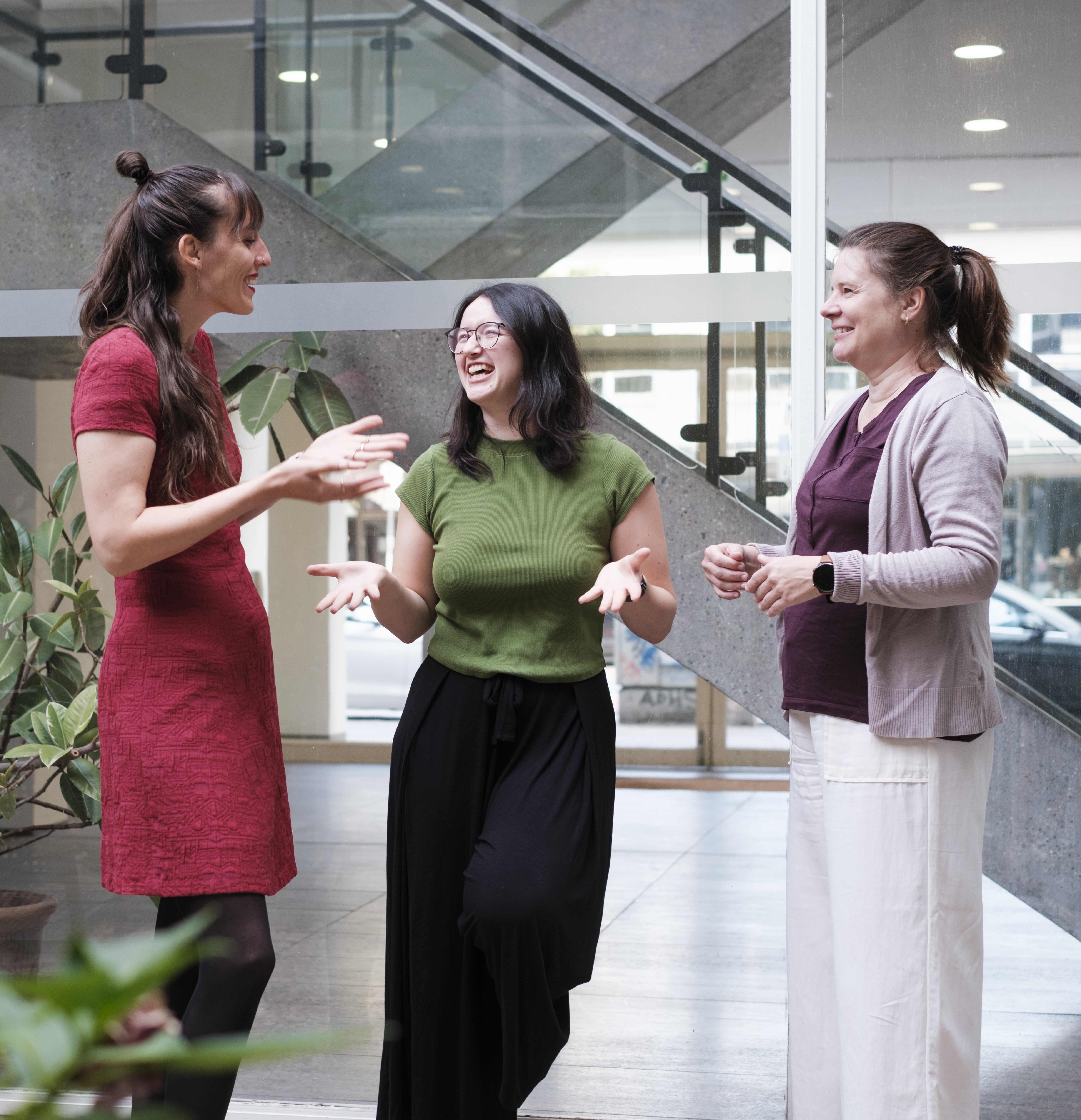 Drei Frauen stehen vor einer Treppe und unterhalten sich.