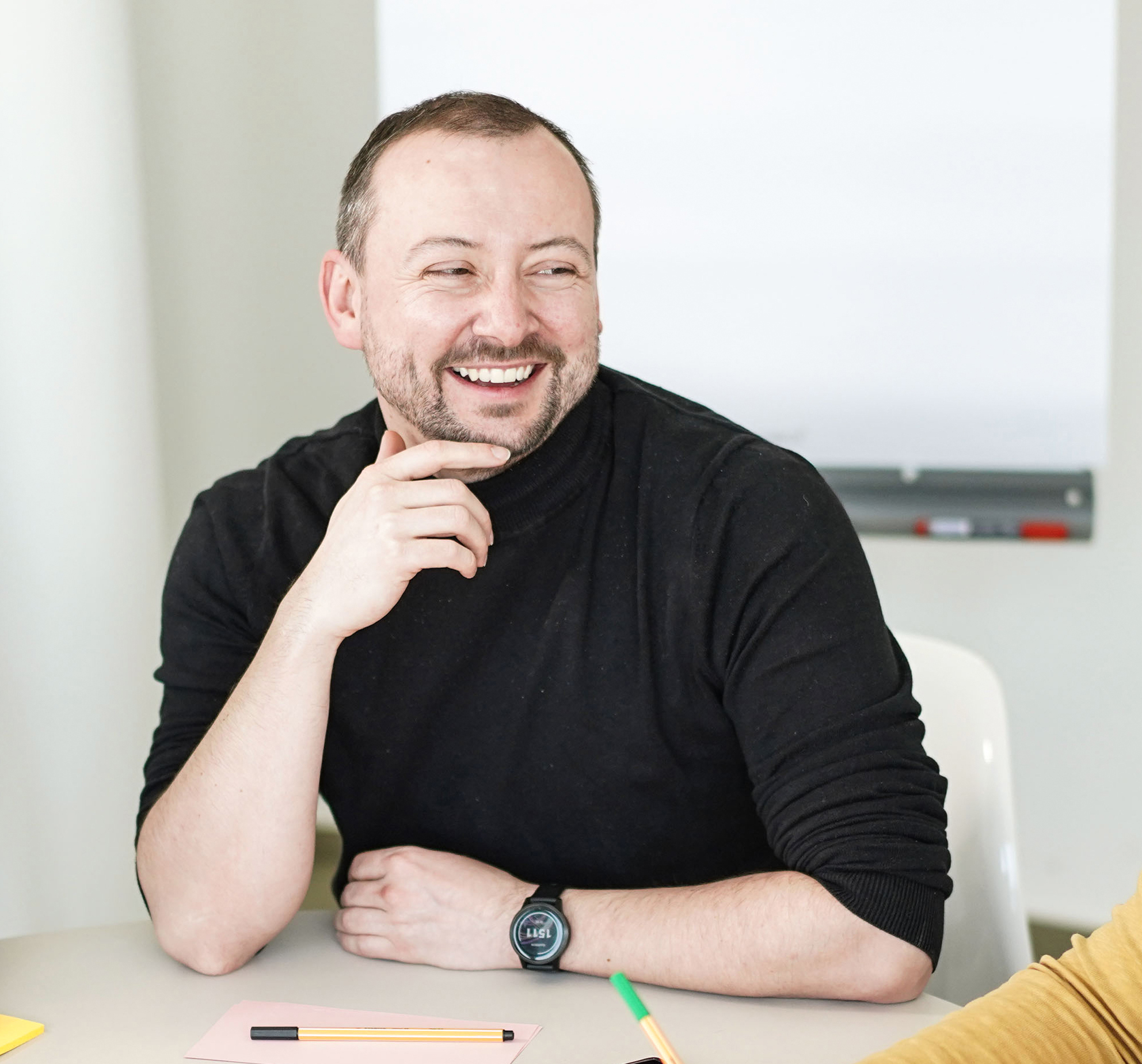 Lachender Paul Kloda sitzt an einem Tisch.
